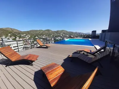 a deck with chairs and a swimming pool on a building at Miralejos 7 Turquesa in Villa Carlos Paz