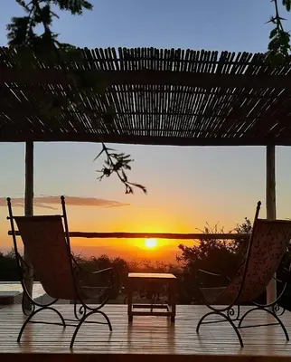 two chairs and a table in front of a sunset at Tantasiña Cabañas Suites de Montaña in San Javier