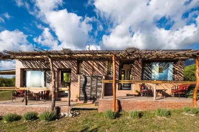 a brick house with a deck and a patio at Tantasiña Cabañas Suites de Montaña in San Javier