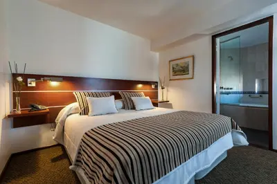 a hotel room with a large bed and a bathroom at Hotel de la Cañada in Cordoba