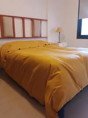 a bed with a yellow blanket on top of it at Departamento Alberdi in Cordoba