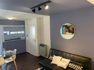 a living room with a black leather couch and a table at Torre Magna II, Nueva Cordoba in Cordoba
