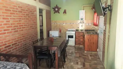 a kitchen with a table and chairs and a brick wall at Luz Alba Cabañas in Mina Clavero