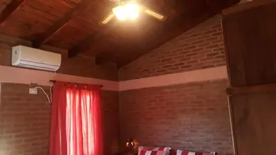 a room with a red curtain and a brick wall at Luz Alba Cabañas in Mina Clavero