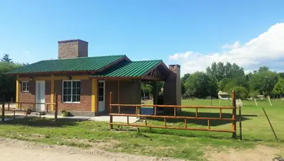 a small house with a green roof on a field at Luz Alba Cabañas in Mina Clavero