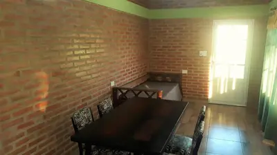 a dining room with a brick wall and a table and chairs at Luz Alba Cabañas in Mina Clavero