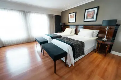 a bedroom with two beds and a wooden floor at Amérian Executive Córdoba in Cordoba