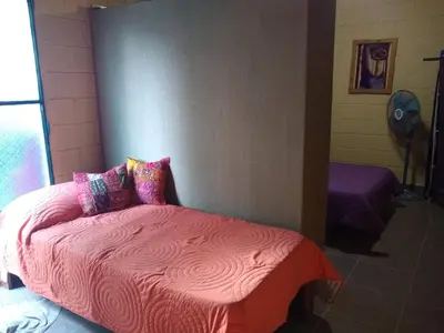a bedroom with a bed with pink sheets and pillows at Dpto La Bicicleta solar in Villa Independencia