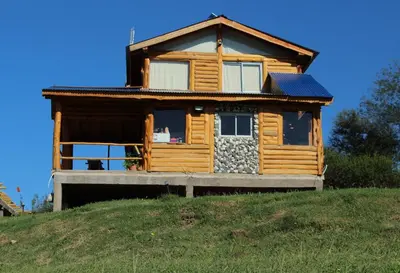a log cabin on a hill with a house at Amaneceres de San Isidro in José de la Quintana