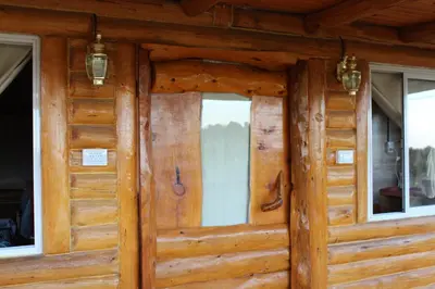 a wooden door of a cabin with two windows at Amaneceres de San Isidro in José de la Quintana
