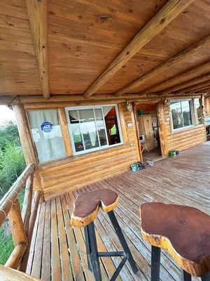 a porch of a cabin with a stool and windows at Amaneceres de San Isidro in José de la Quintana
