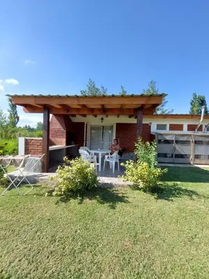 a man sitting on the porch of a house at Cabañas Matices del Lago in Villa Ciudad Parque
