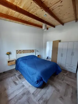a large blue bed in a room with a wooden ceiling at Cabañas Matices del Lago in Villa Ciudad Parque