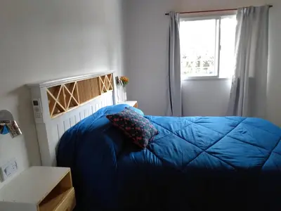 a bedroom with a blue bed and a window at Cabañas Matices del Lago in Villa Ciudad Parque