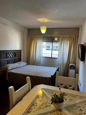 a bedroom with a bed and a table and chairs at Punto Quiros - Monoambiente centrico, a la vuelta del Patio Olmos in Cordoba