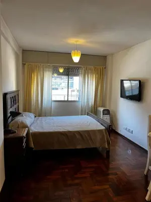 a bedroom with a large bed and a television at Punto Quiros - Monoambiente centrico, a la vuelta del Patio Olmos in Cordoba