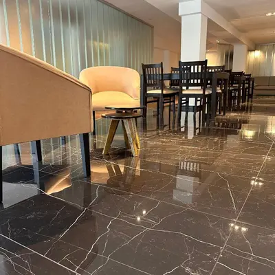 a dining room with tables and chairs on a marble floor at Hotel 376 in Villa Carlos Paz