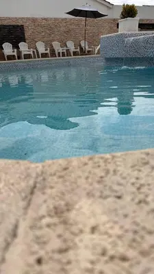 a swimming pool with chairs and an umbrella at Hotel 376 in Villa Carlos Paz