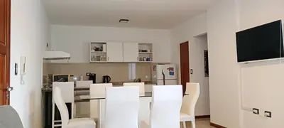 a white kitchen with white chairs and a table at Departamento centrico carlos paz in Villa Carlos Paz