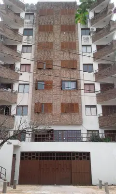 a tall building with a brown gate in front of it at Departamento Centro Villa Carlos Paz in Villa Carlos Paz