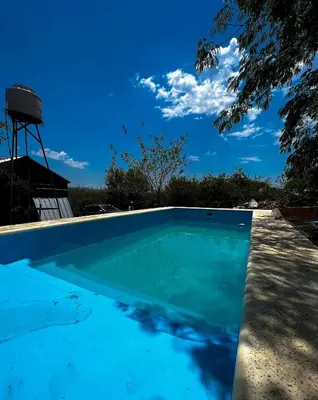 a blue swimming pool with a water tower in the background at el PARAISO in Villa Anizacate