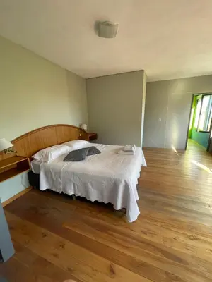 a bedroom with a bed and a wooden floor at Casas Pura Vida in Villa General Belgrano
