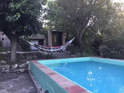 a hammock by a swimming pool next to a house at La Quebradita in San Javier