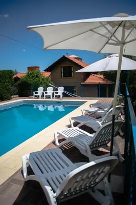 a group of lounge chairs with an umbrella next to a pool at Cabañas Monteolivos in Merlo