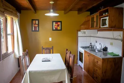 a kitchen with a table and a kitchen with yellow walls at Cabañas Monteolivos in Merlo