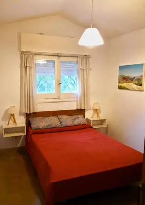 a bedroom with a red bed and two windows at Casa en Villa Amancay in Amboy