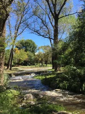 a stream in a park with trees and a bridge at Casa en Villa Amancay in Amboy
