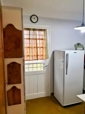 a kitchen with a refrigerator and a clock on the wall at Casa en Villa Amancay in Amboy