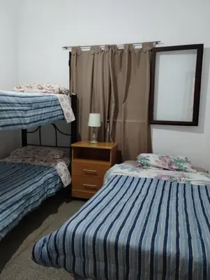 a bedroom with two beds and a dresser and a window at Buenas Vibras in Villa Carlos Paz