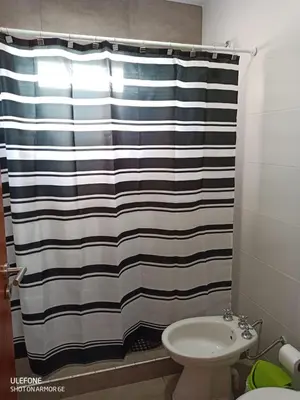 a bathroom with a black and white shower curtain at Bº CERRADO LOMAS DEL REY MAYU SUMAJ in San Antonio de Arredondo