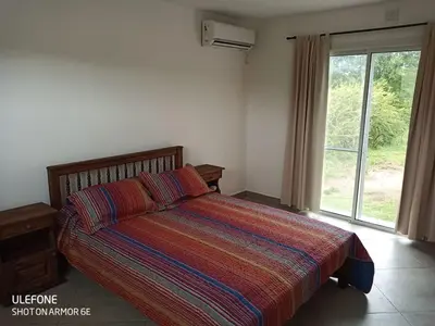a bedroom with a bed with a colorful blanket and a window at Bº CERRADO LOMAS DEL REY MAYU SUMAJ in San Antonio de Arredondo