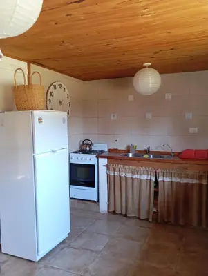 a kitchen with a white refrigerator and a stove at Mirador de Atuq - Casa Serrana in Villa Yacanto