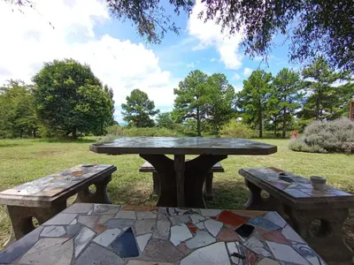a picnic table and two benches in a park at Mirador de Atuq - Casa Serrana in Villa Yacanto