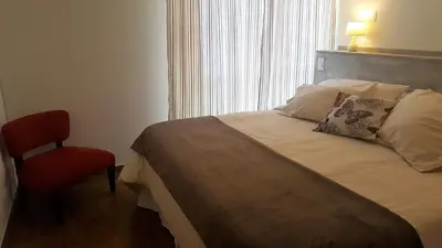 a bedroom with a bed and a red chair at Luminoso departamento en Cañada y a pasos de todo! in Cordoba