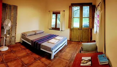 a bedroom with a bed and a chair and windows at apartamento VINTAGE IVA in Merlo