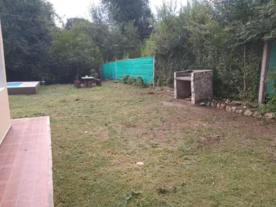 a backyard with a green fence and a grass field at Casa con pileta privada in Tanti