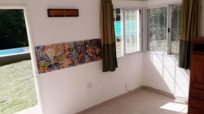 a room with white walls and windows with a painting on the wall at Casa con pileta privada in Tanti