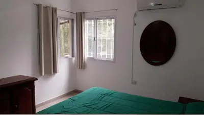 a bedroom with a green bed and two windows at Casa con pileta privada in Tanti