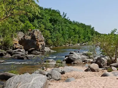 a river with rocks and people swimming in it at Cabaña El Canal in Villa Carlos Paz