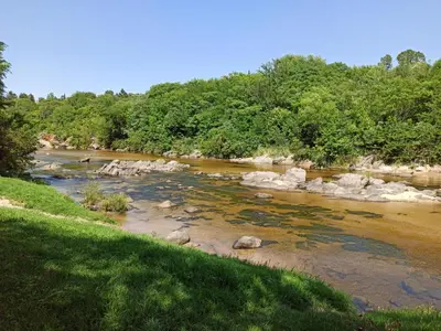 a river with rocks and trees in the background at Cabaña El Canal in Villa Carlos Paz