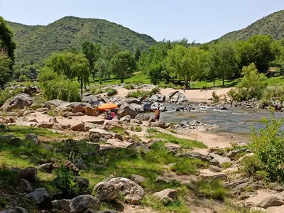 people standing on the rocks near a river at Cabaña El Canal in Villa Carlos Paz