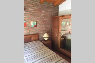 a bedroom with a bed and a brick wall at Santa Rosa con parque y rio Ideal para familias in Santa Rosa de Calamuchita