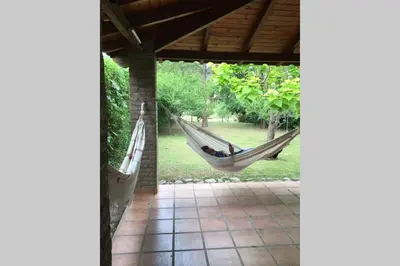 a man sleeping in a hammock in a porch at Santa Rosa con parque y rio Ideal para familias in Santa Rosa de Calamuchita