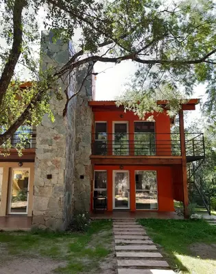 a house with an orange facade and a tree at Complejo Verde Memoria in Merlo