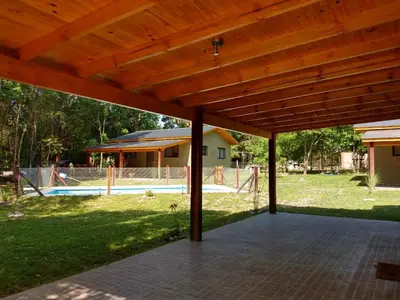 a wooden pergola over a patio with a pool at Complejo El Bosque in Villa Ciudad Parque