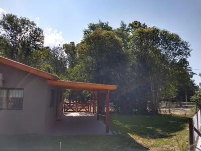 a building with a porch with a fence and trees at Complejo El Bosque in Villa Ciudad Parque